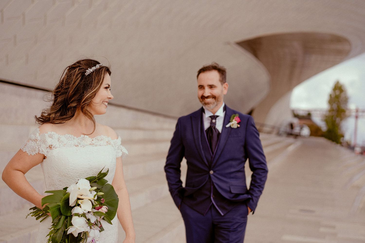 Couple smiling and laughing together at a wedding while walking down a stone walkway.
