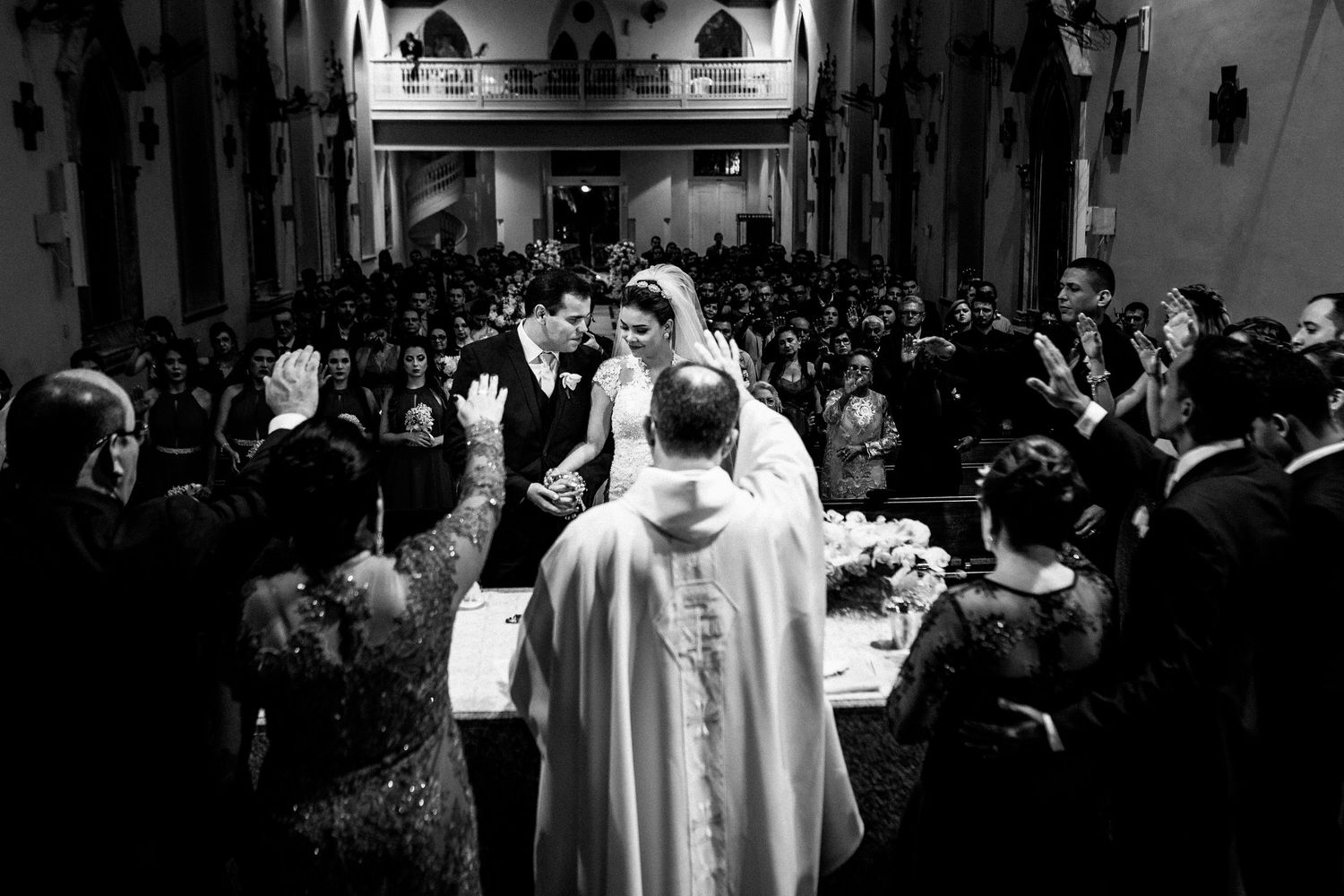 Black and white shot of crowd gathered in church pews during wedding ceremony.