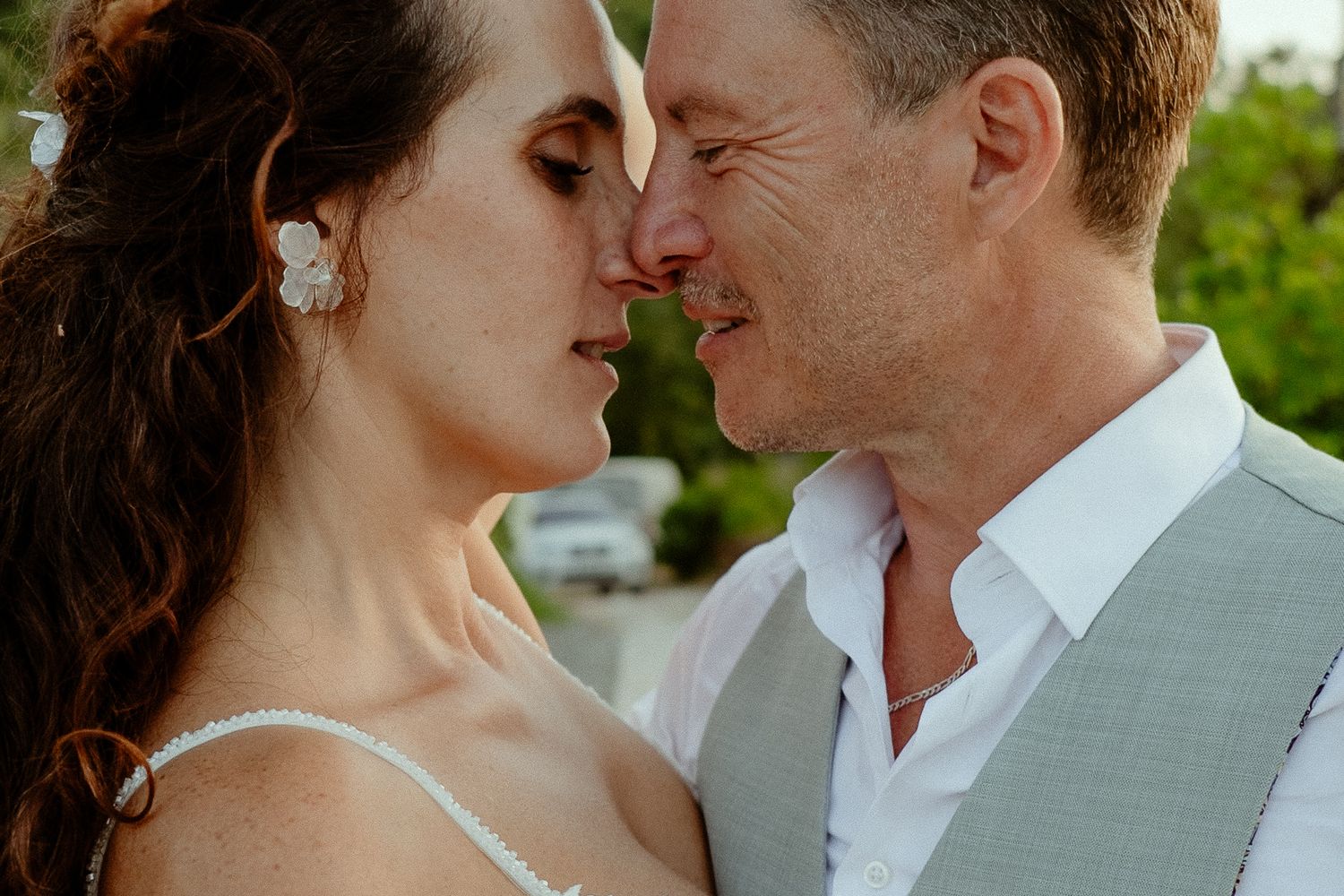 Romantic close-up of bride and groom sharing an intimate moment outdoors on their wedding day.