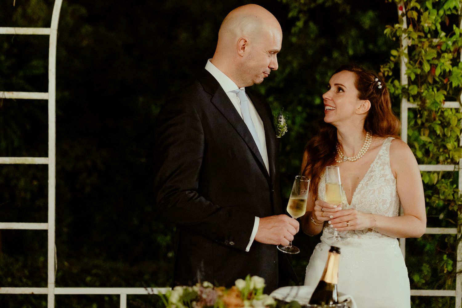 A bride and groom toast with champagne glasses at their elegant outdoor wedding reception.