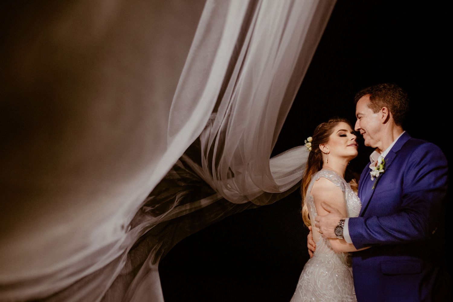 A romantic sequence of wedding photos showing the couple sharing intimate kisses under flowing veils and dramatic lighting.
