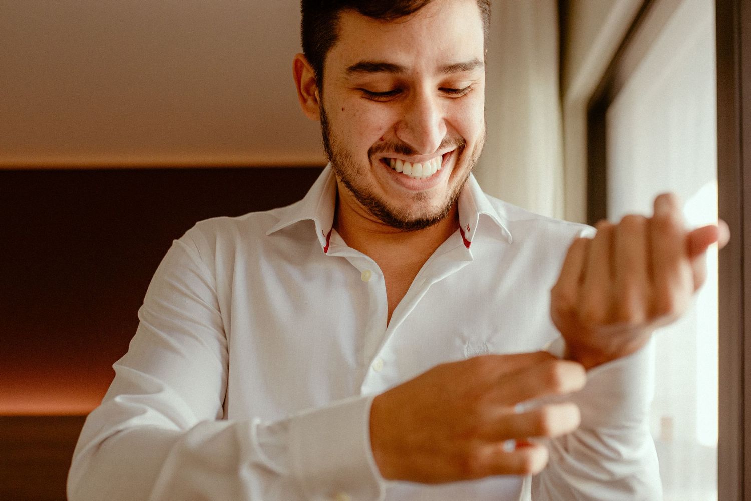 Smiling person in a white button-down shirt works while gesturing with their hands in an office setting.