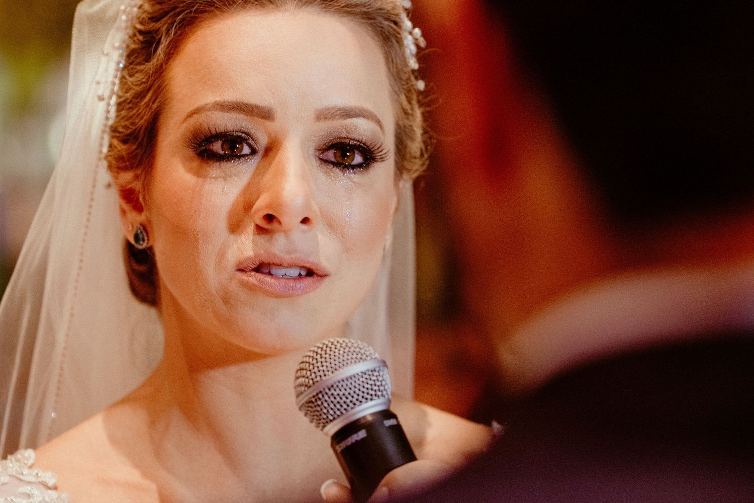 A close-up black and white shot of an emotional moment with a microphone during wedding vows.