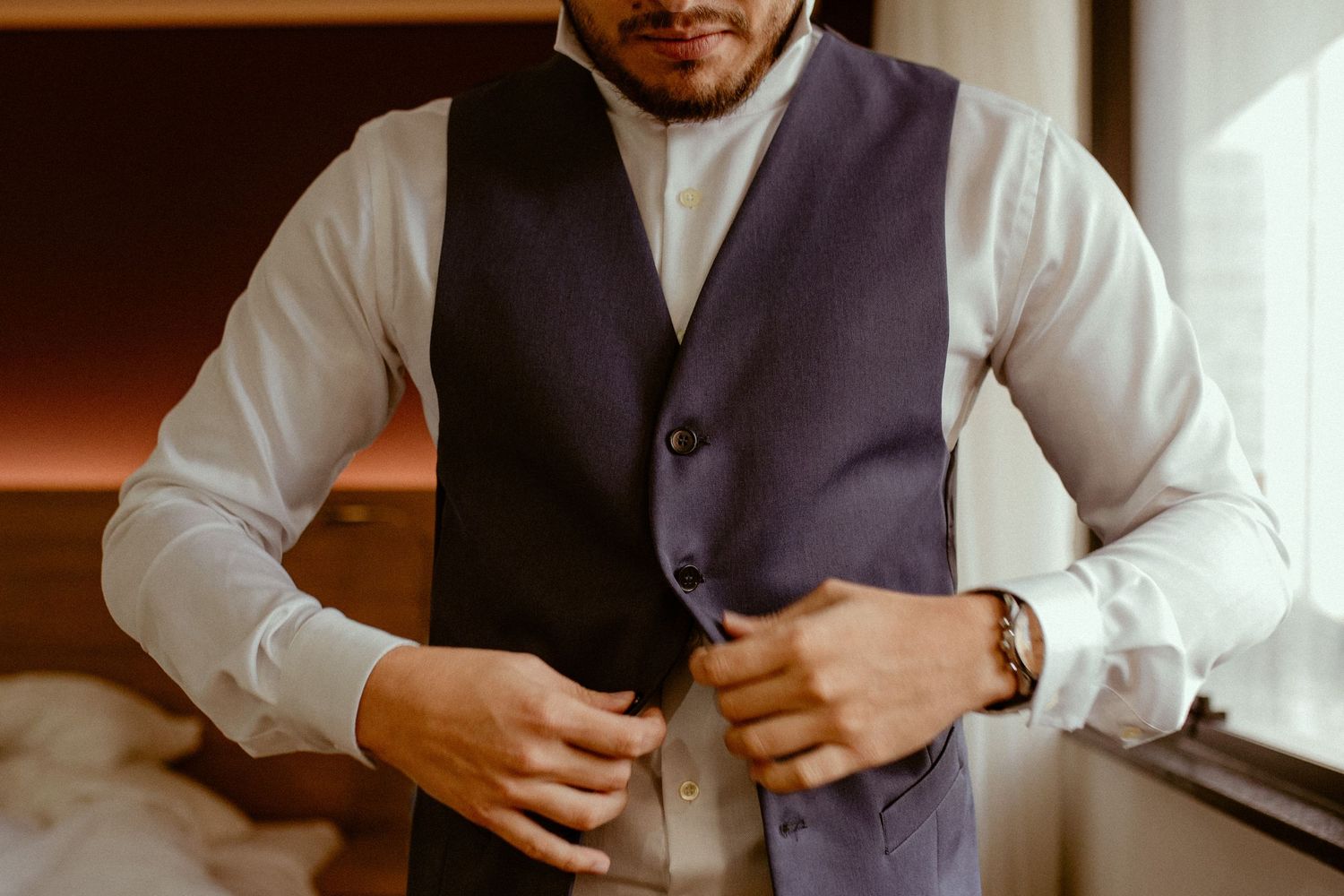 Close-up shots of someone adjusting and buttoning a formal grey vest over a white dress shirt.