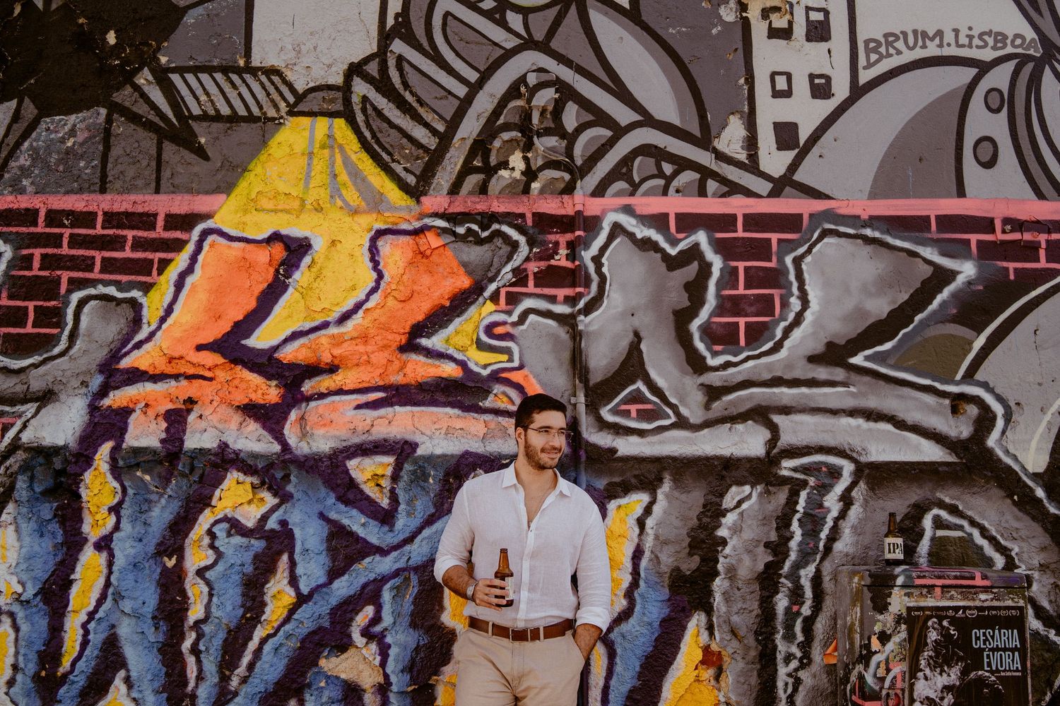 Colorful graffiti artwork covers a brick wall with vibrant yellow and blue designs in an urban setting.