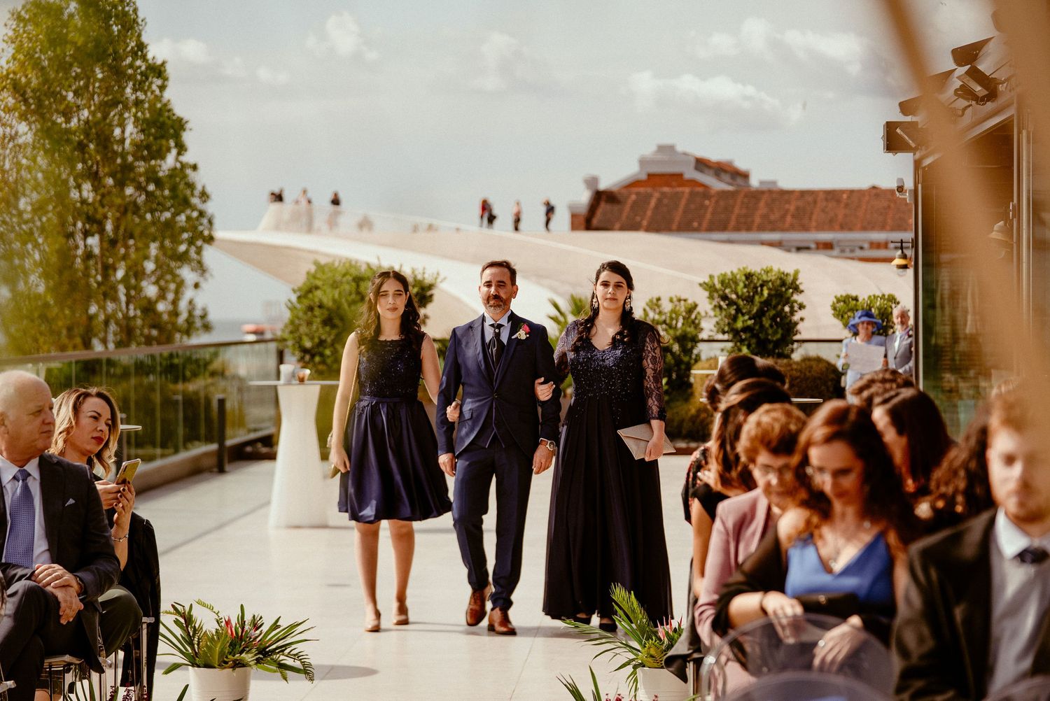 Wedding guests gathered on an elegant rooftop terrace for outdoor ceremony.