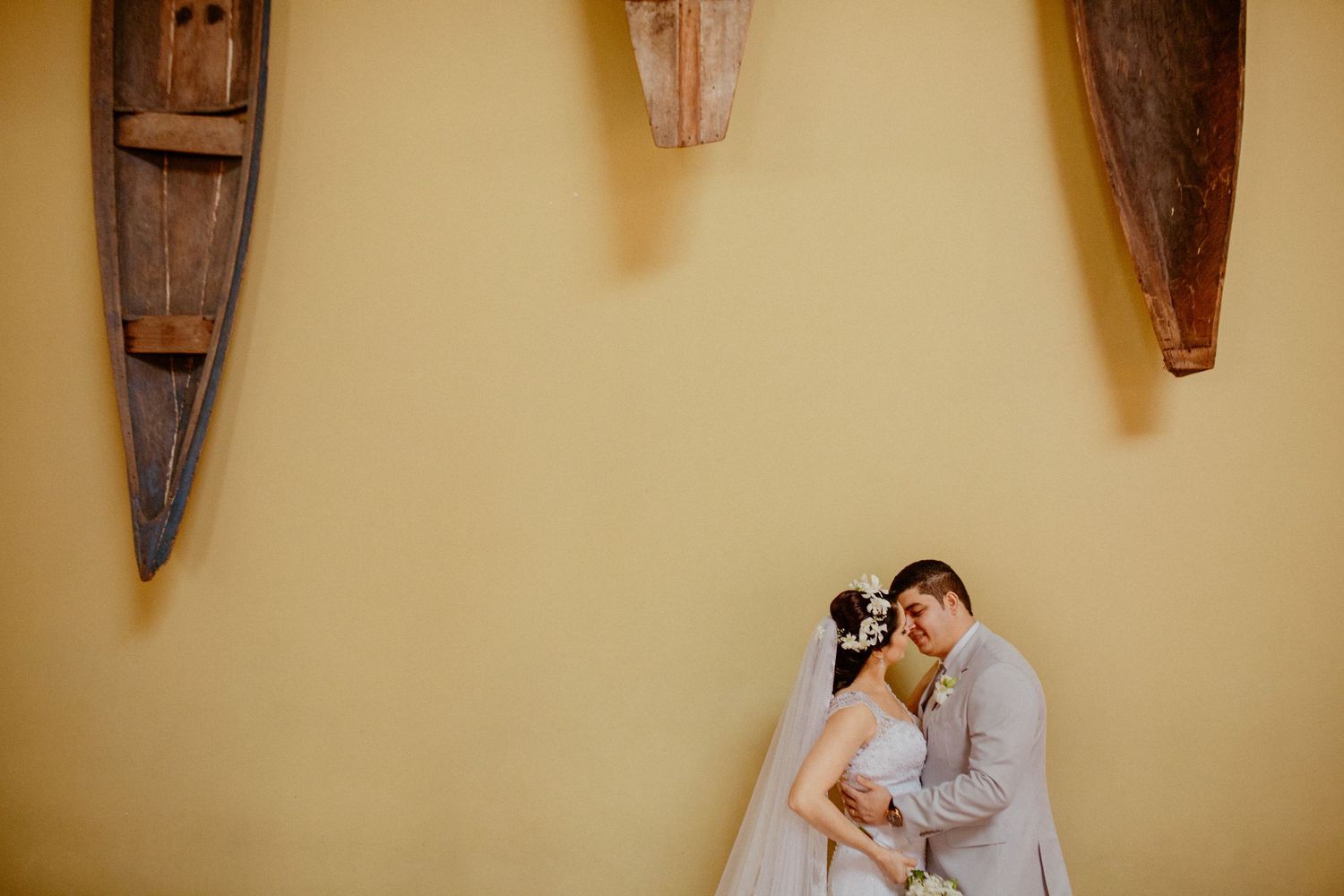 Intimate wedding portrait against yellow wall with decorative canoes.