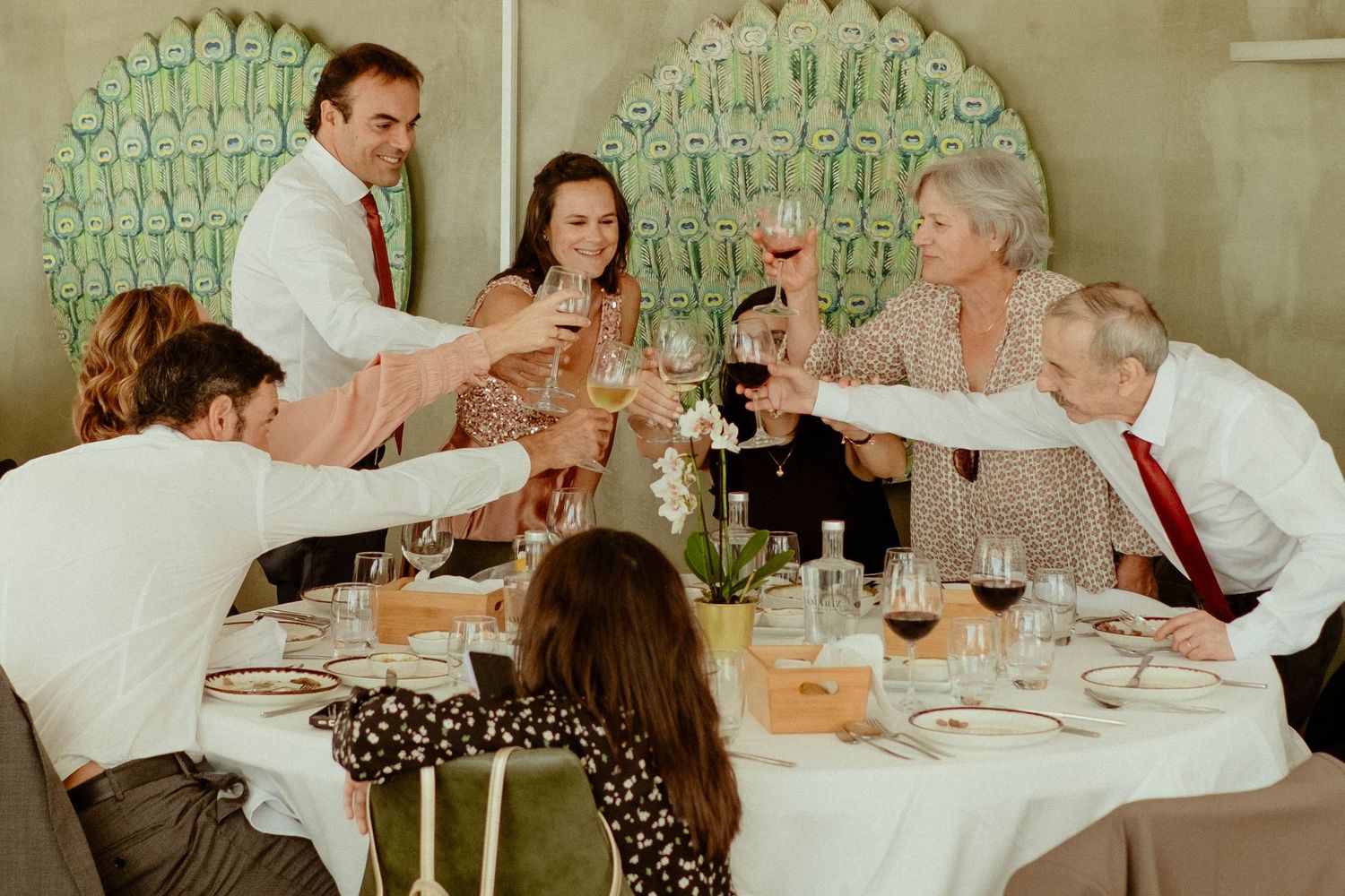 Wedding guests raise champagne glasses in a celebratory toast against a backdrop of empty wine glasses.