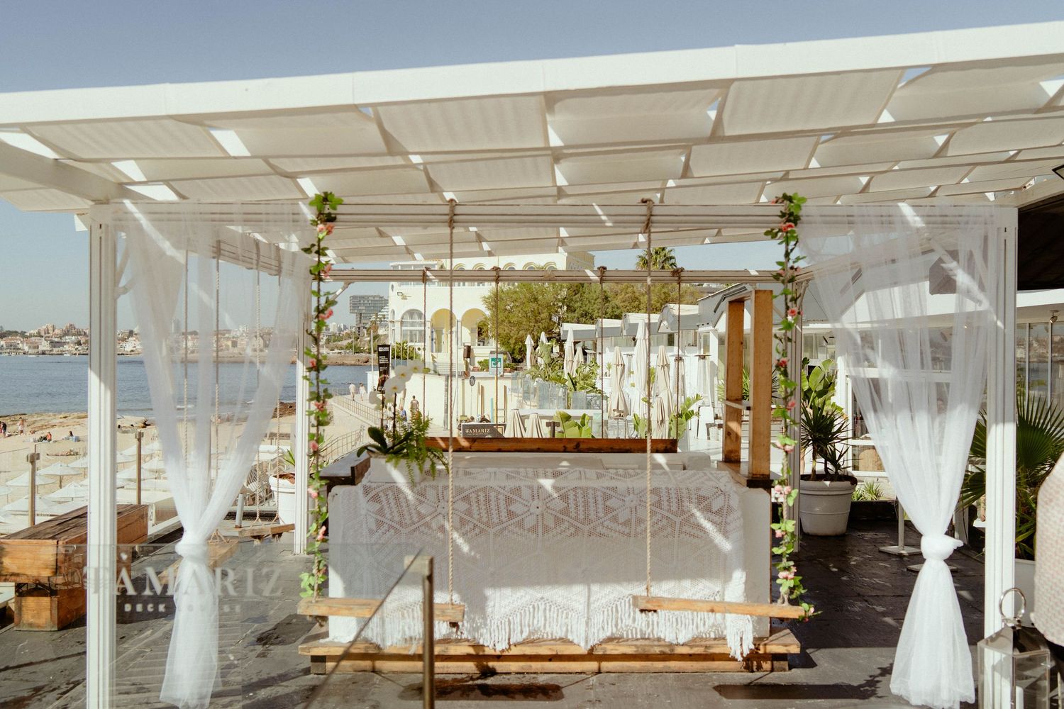 Elegant white wedding reception venue with draped fabric, chandeliers, and floral arrangements creating a romantic atmosphere.
