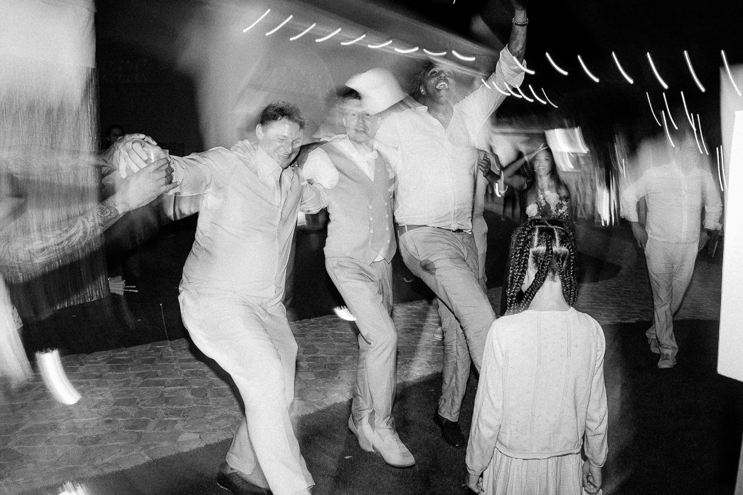 Black and white photo of people energetically dancing at a lively party or dance hall event.