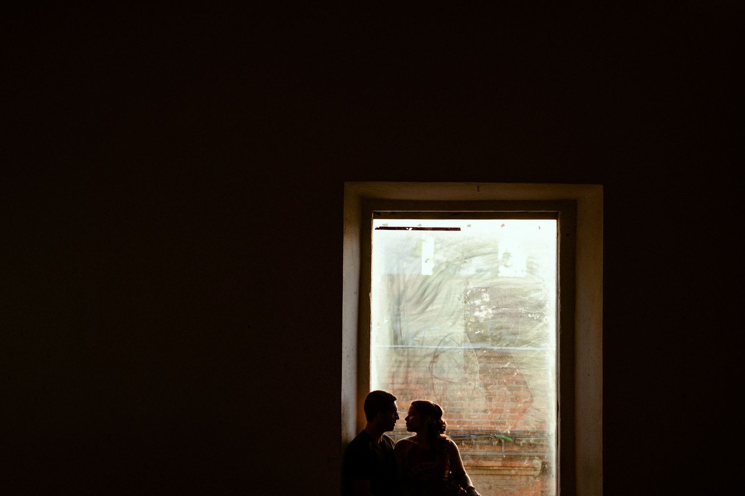 A sequence of dim windows showing views to the outside in a dark interior space.