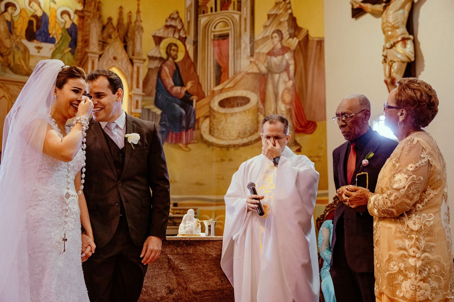 Wedding ceremony in a church with religious murals and clergy officiating.