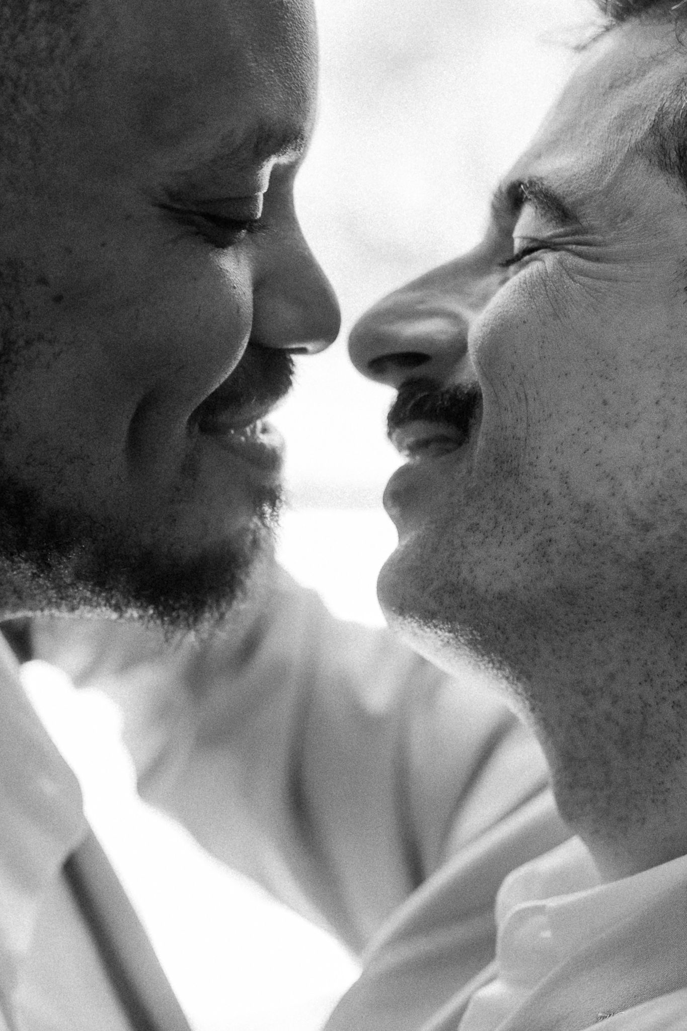 Black and white close-up of two smiling people facing each other, sharing an intimate romantic moment.