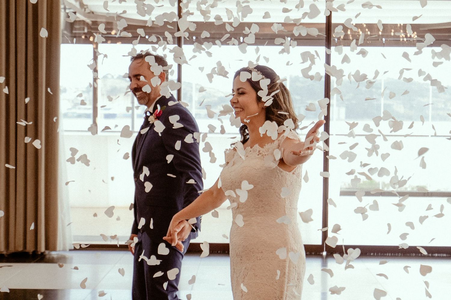 Couple celebrates joyfully in a room as confetti falls during their wedding celebration.