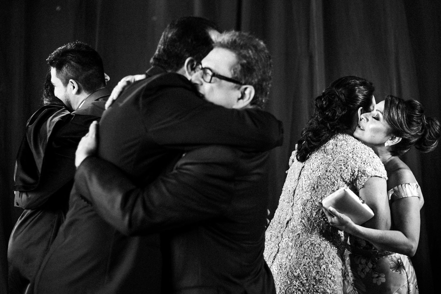 Black and white photo of emotional embraces during wedding reception celebrations.