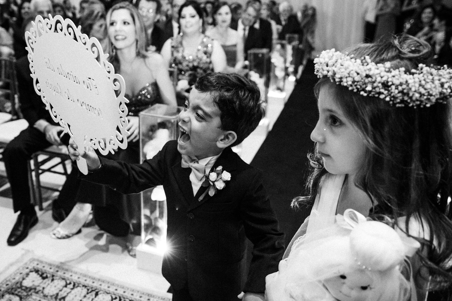 Two young attendants wearing floral crowns during a wedding ceremony.