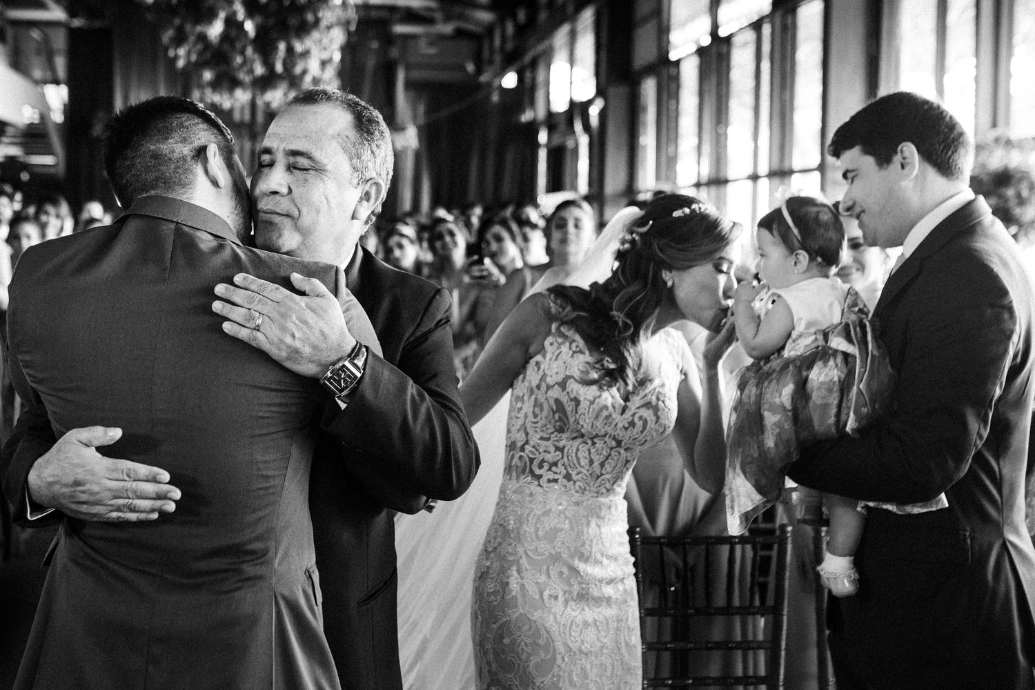 Multiple snapshots of an emotional wedding scene showing couples hugging and embracing in black and white photography.