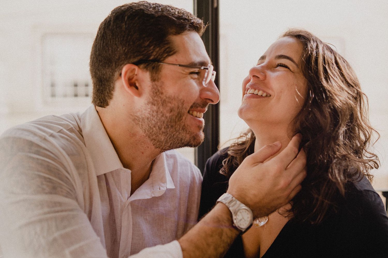 A couple shares an intimate laughing moment together during a candid photoshoot.