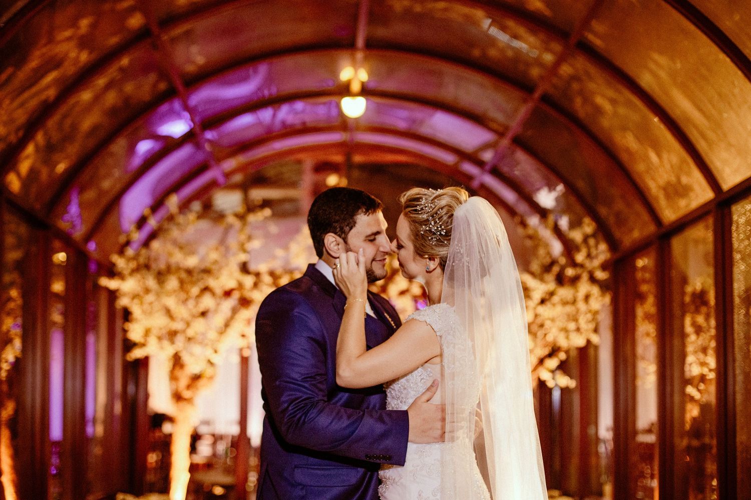 A romantic moment captured in a warmly lit tunnel decorated with glowing cherry blossoms.