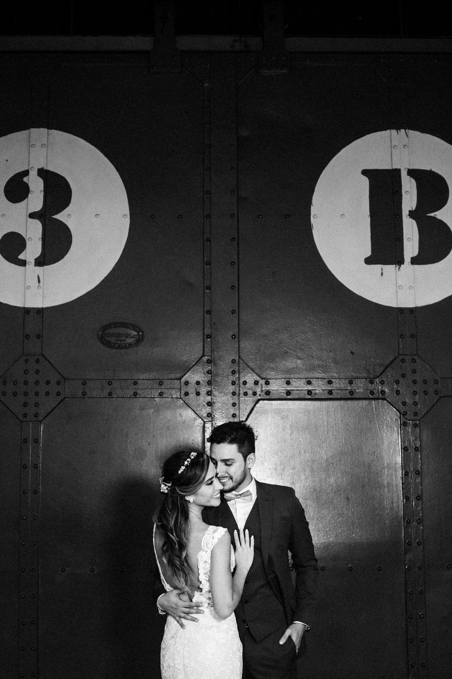 A romantic black and white wedding photo sequence showing intimate moments between newlyweds against an industrial wall.