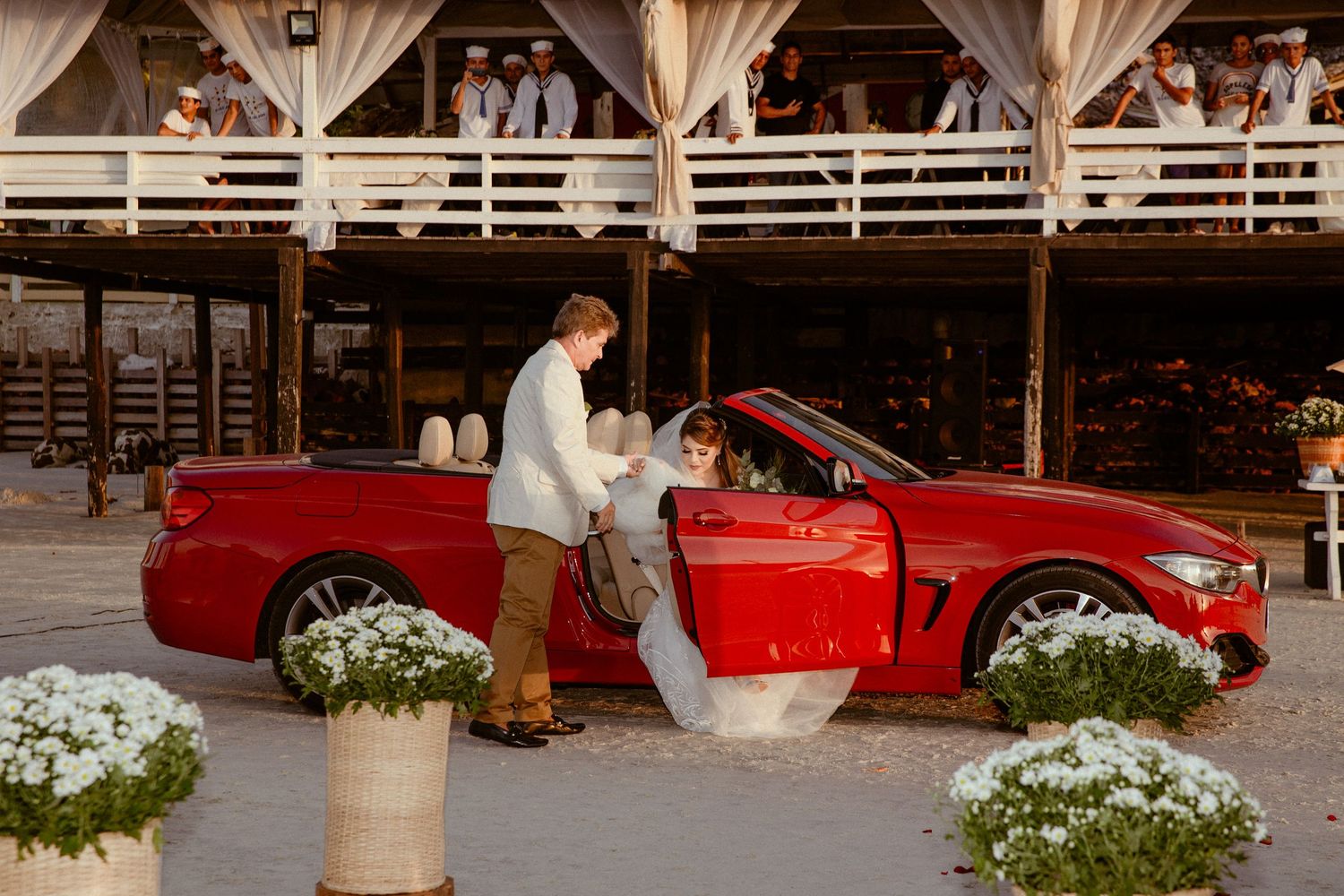 A sequence of photos showing a red sports car parked at a venue with decorative white fabric draping.