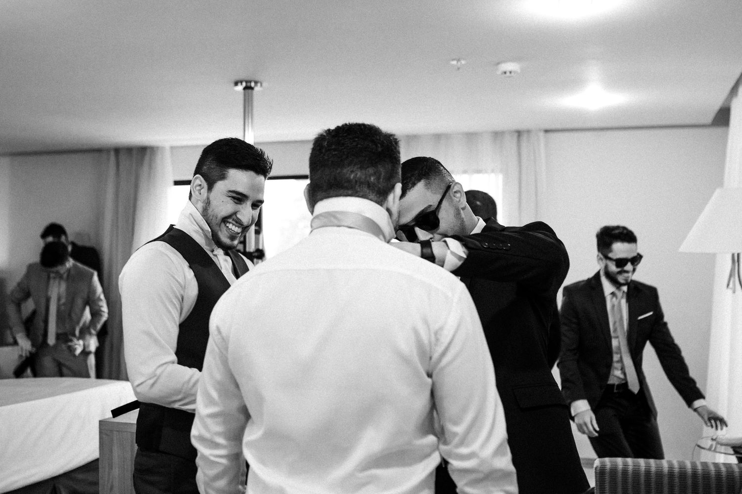 Group of professionally dressed people gathered in a bright office hallway having conversations.