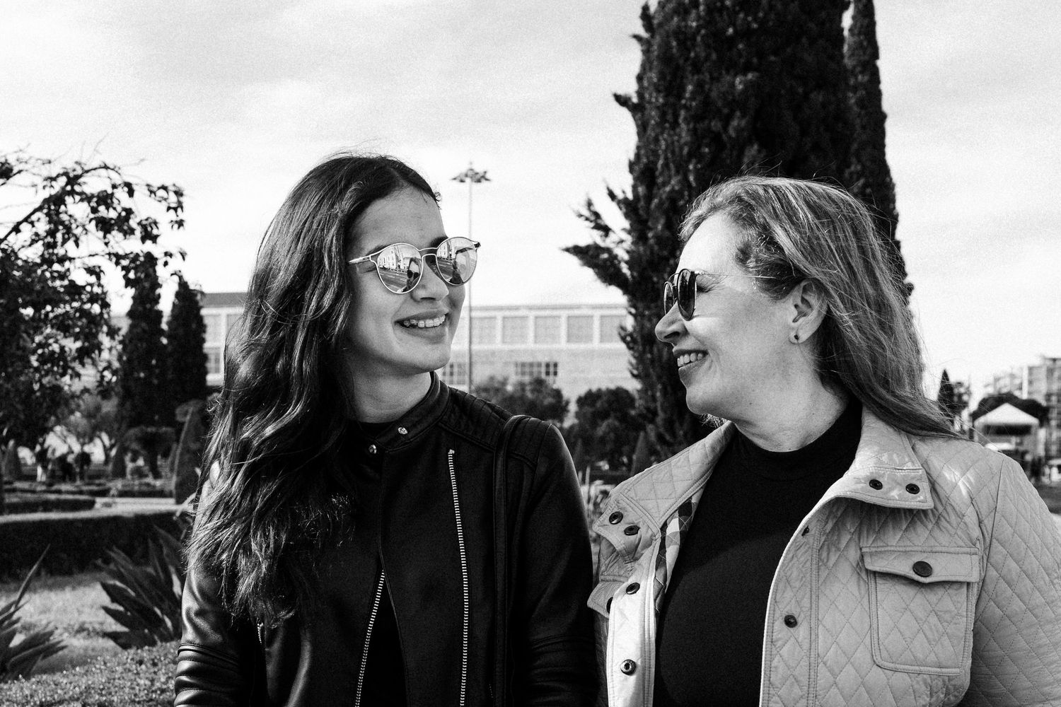 Black and white portrait of two friends laughing together outdoors.