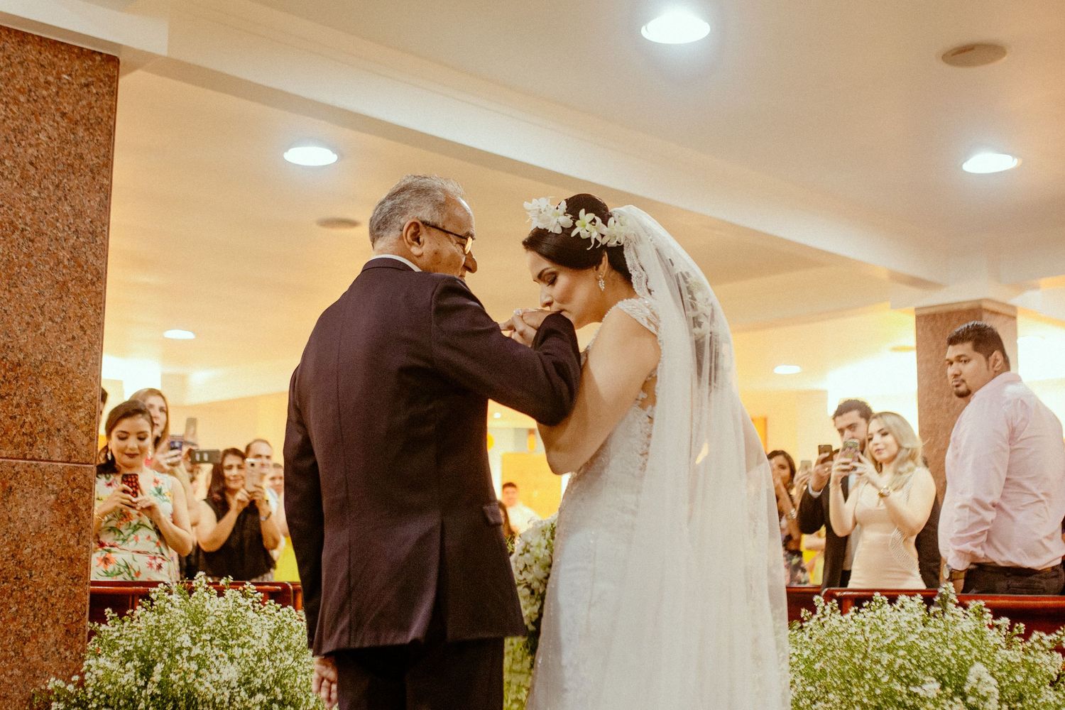 Intimate wedding ceremony moment with guests watching in an indoor venue.