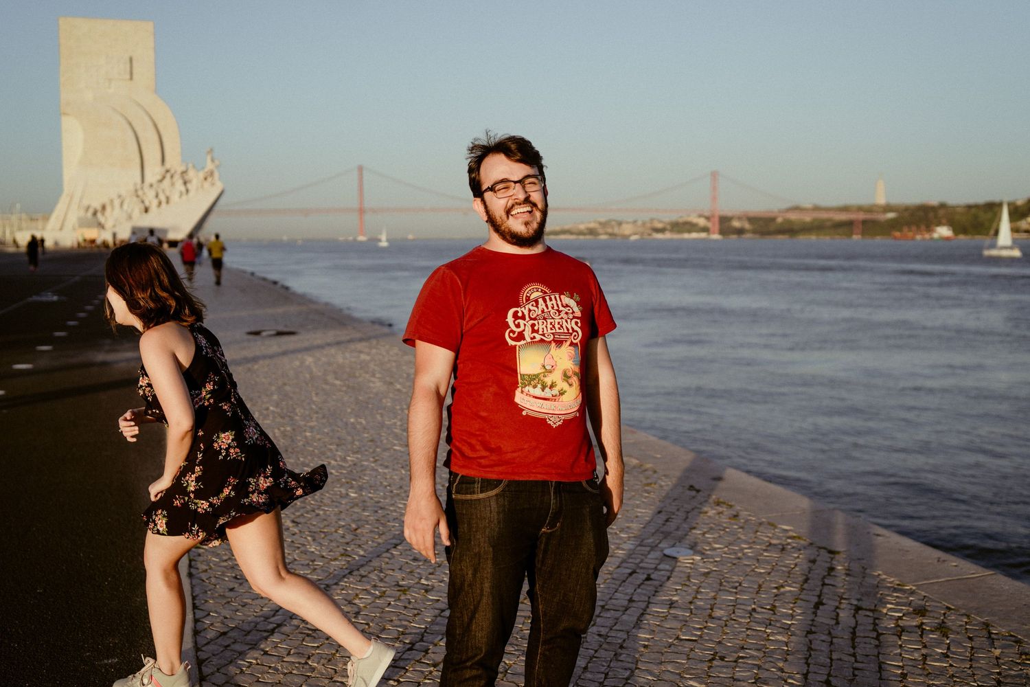 People enjoying a sunny evening along the waterfront near the Monument of Discoveries in Lisbon, Portugal.