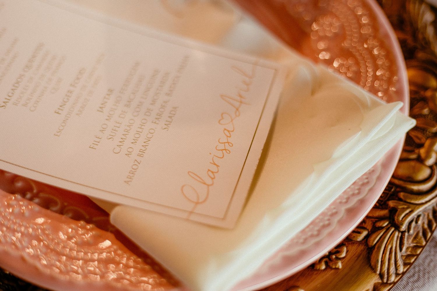 Elegant wedding invitation menu rests on a decorative rose gold plate with ornate details and floral accents.