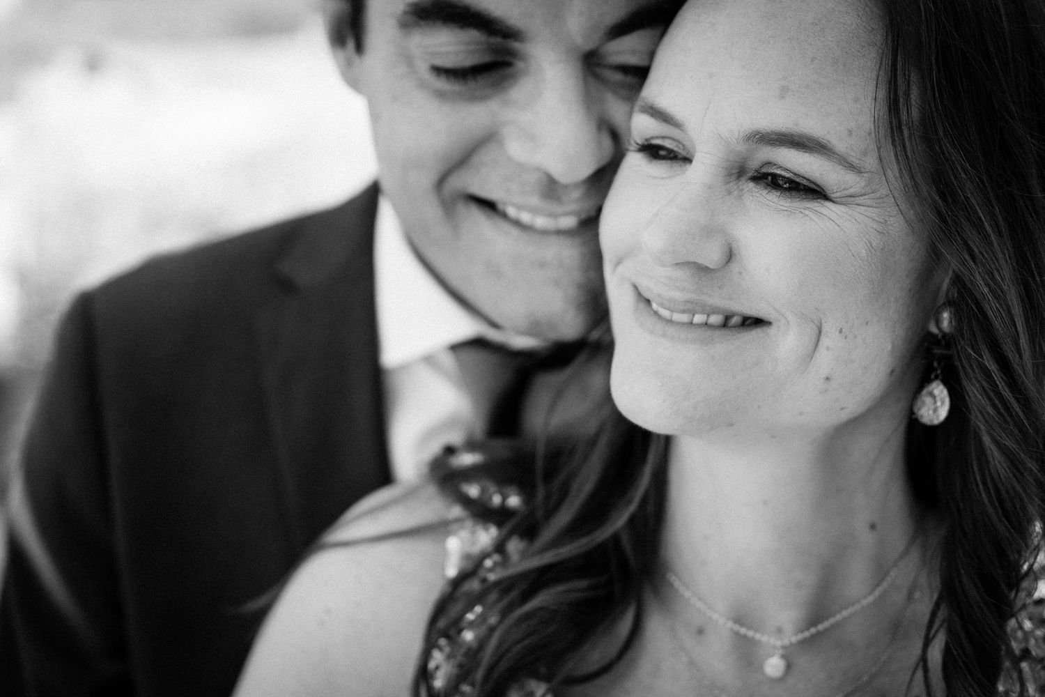 Black and white candid photo showing a joyful couple laughing together during an intimate moment.