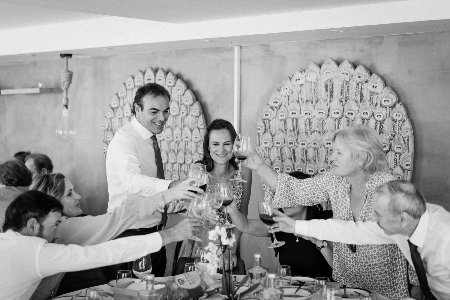 A black and white photograph showing people gathered at a bar or restaurant with decorative circular wall displays.