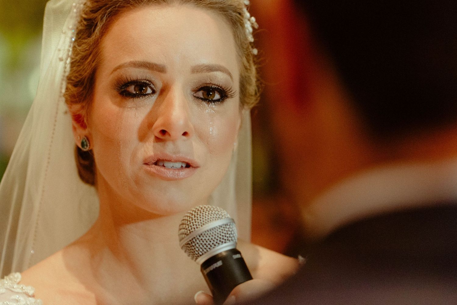 A performer holds a microphone while singing on stage with dramatic lighting and makeup.