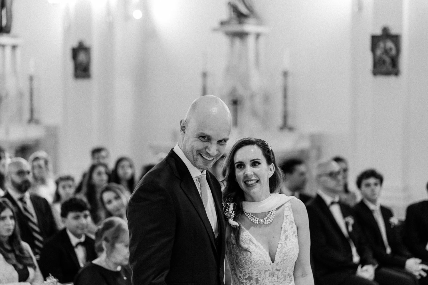 Black and white photo of a smiling bride and groom standing at the altar during their church wedding ceremony.