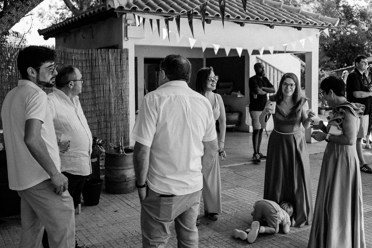 Black and white photo of guests socializing outdoors at a casual garden party event.