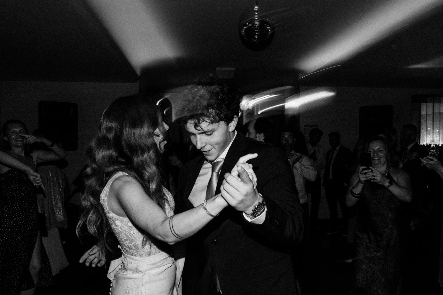 Black and white photo of a couple sharing a romantic dance at a wedding reception on the dance floor.