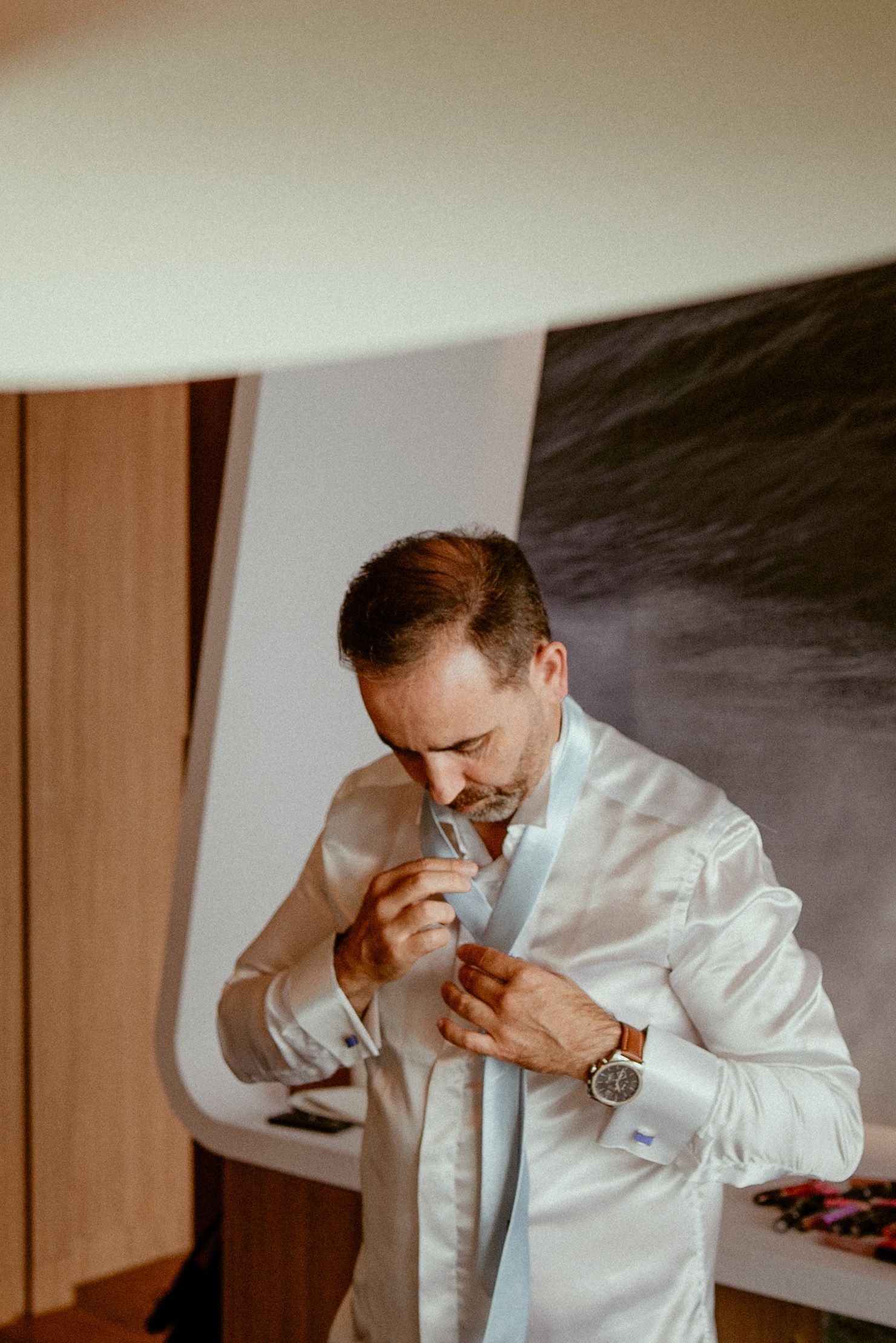 Sequential images of someone in a white dress shirt adjusting something near their neck.