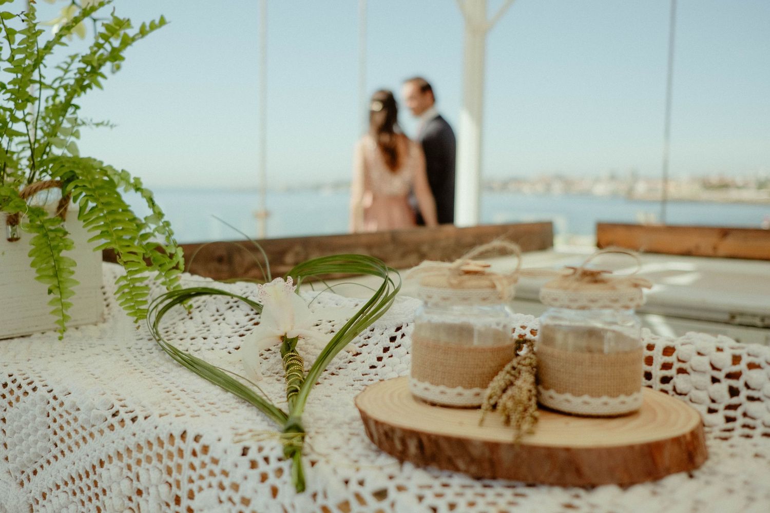 Rustic wedding decor features wood slices, delicate lace doilies, and fresh green fern sprigs on a white tablecloth.