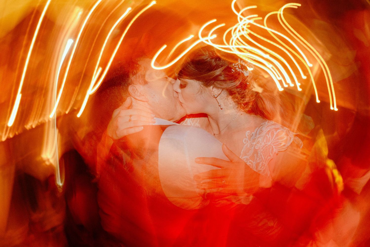 Artistic long exposure shot creating streaks of orange light during a wedding dance.