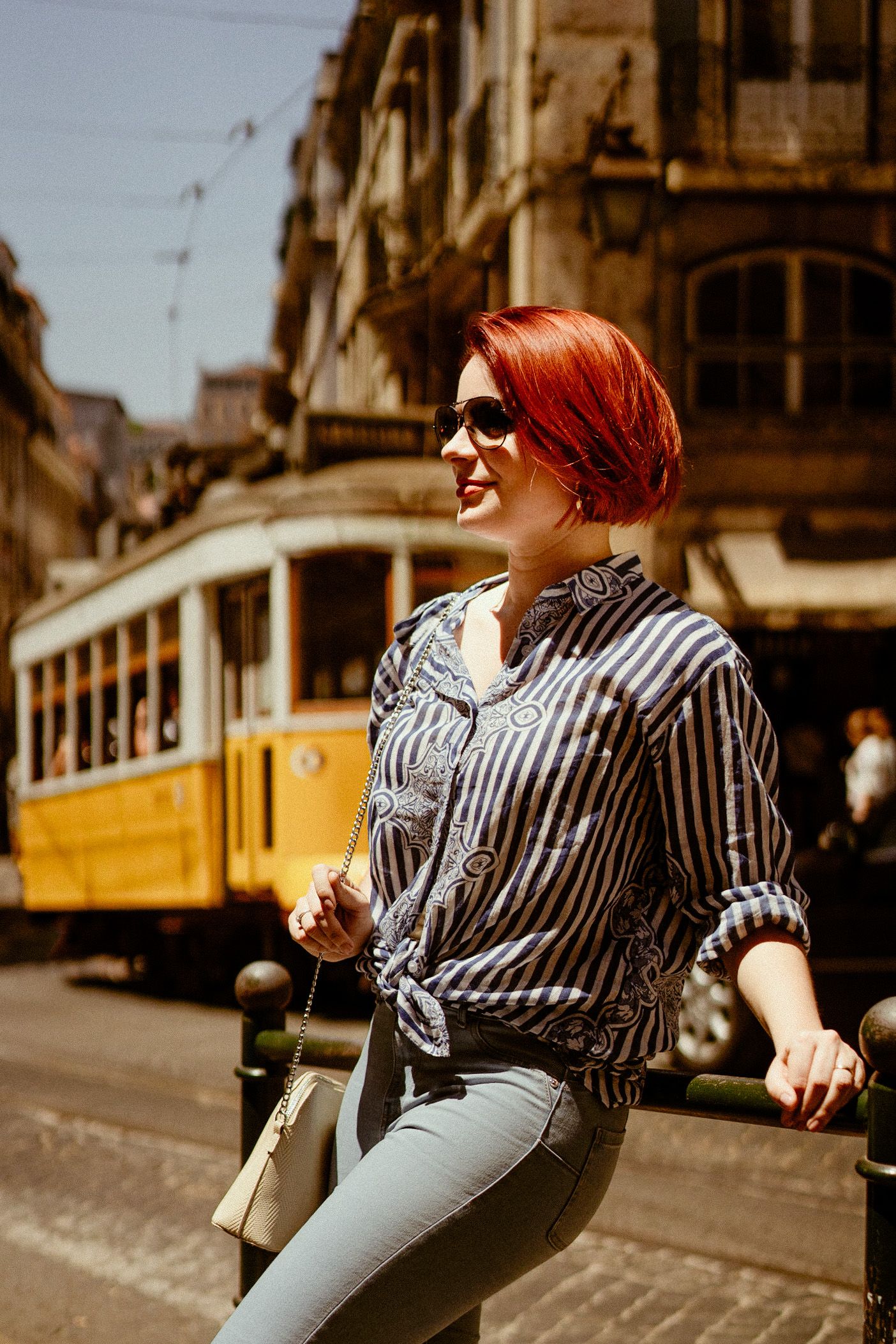 Vintage yellow tram on cobblestone street in historic Lisbon with classic architecture.