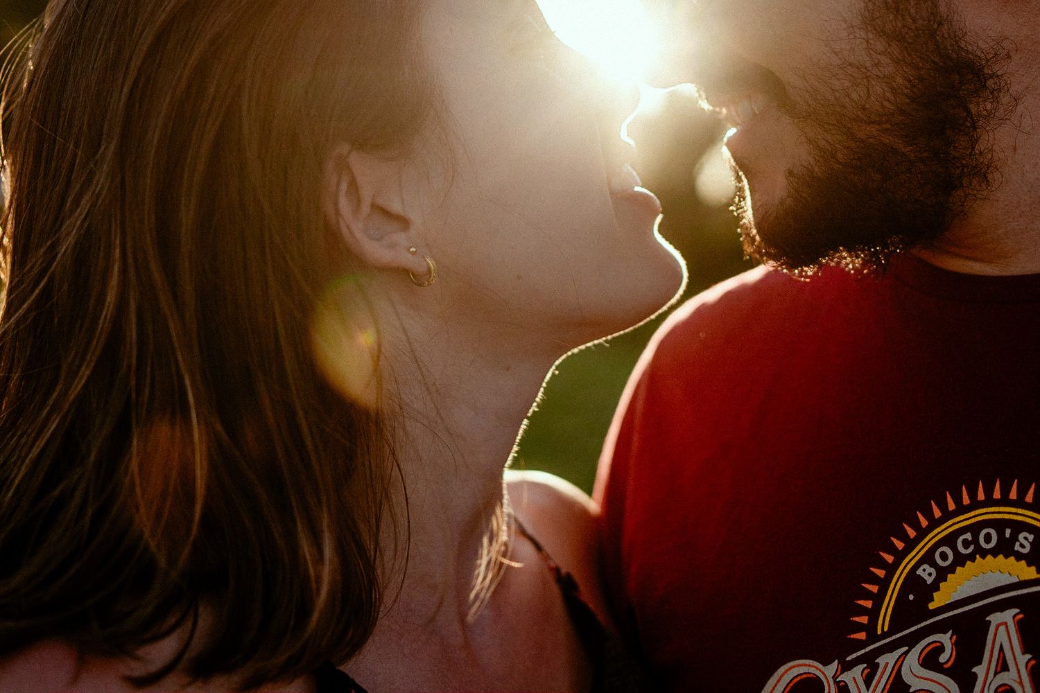 A silhouetted couple in casual clothing share an intimate moment as sunlight bursts between them.