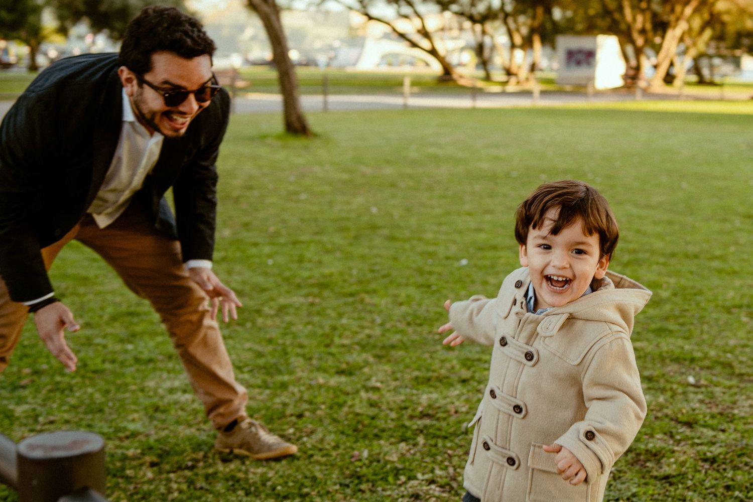 A joyful interaction between parent and child playing together on a sunny grass lawn in the park.