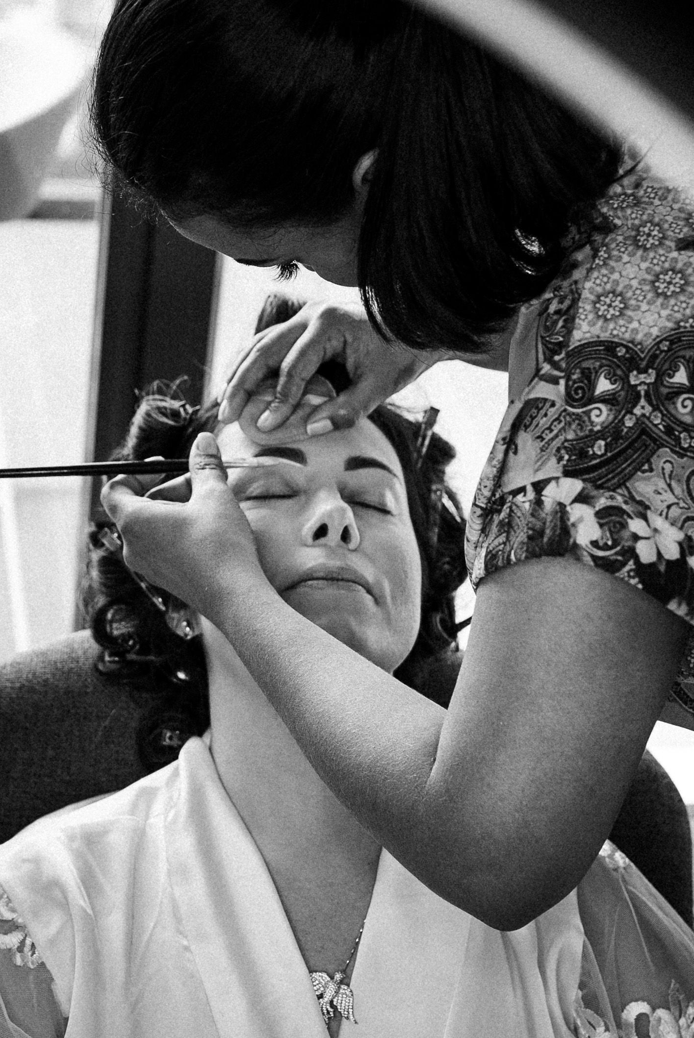 Series of black and white photos showing makeup application on someone's eyes and face.