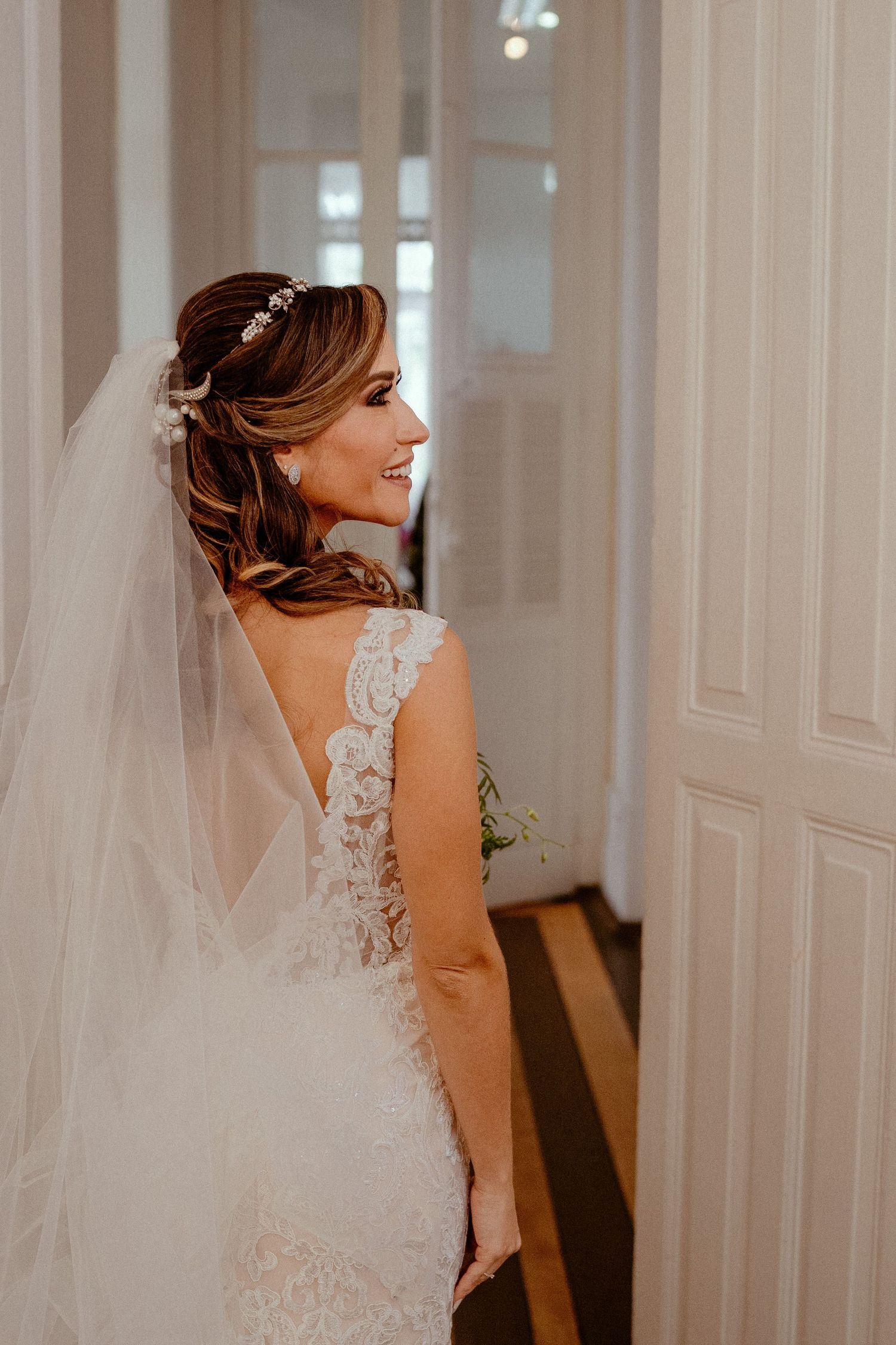 Bride in a sleeveless lace wedding gown turns gracefully during what appears to be a pre-ceremony moment.