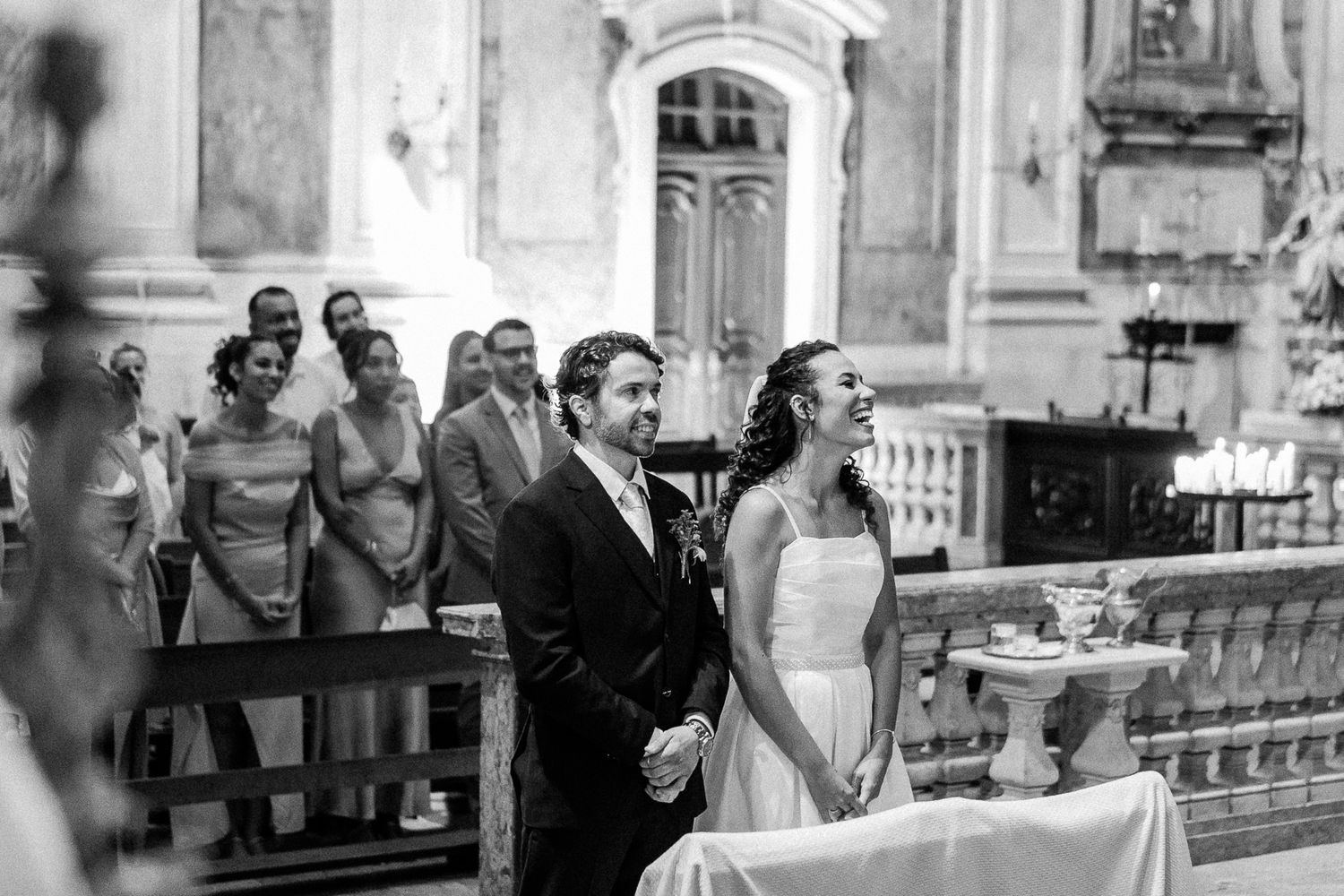 Black and white photo of a smiling bride and groom standing at the altar during their church wedding ceremony.