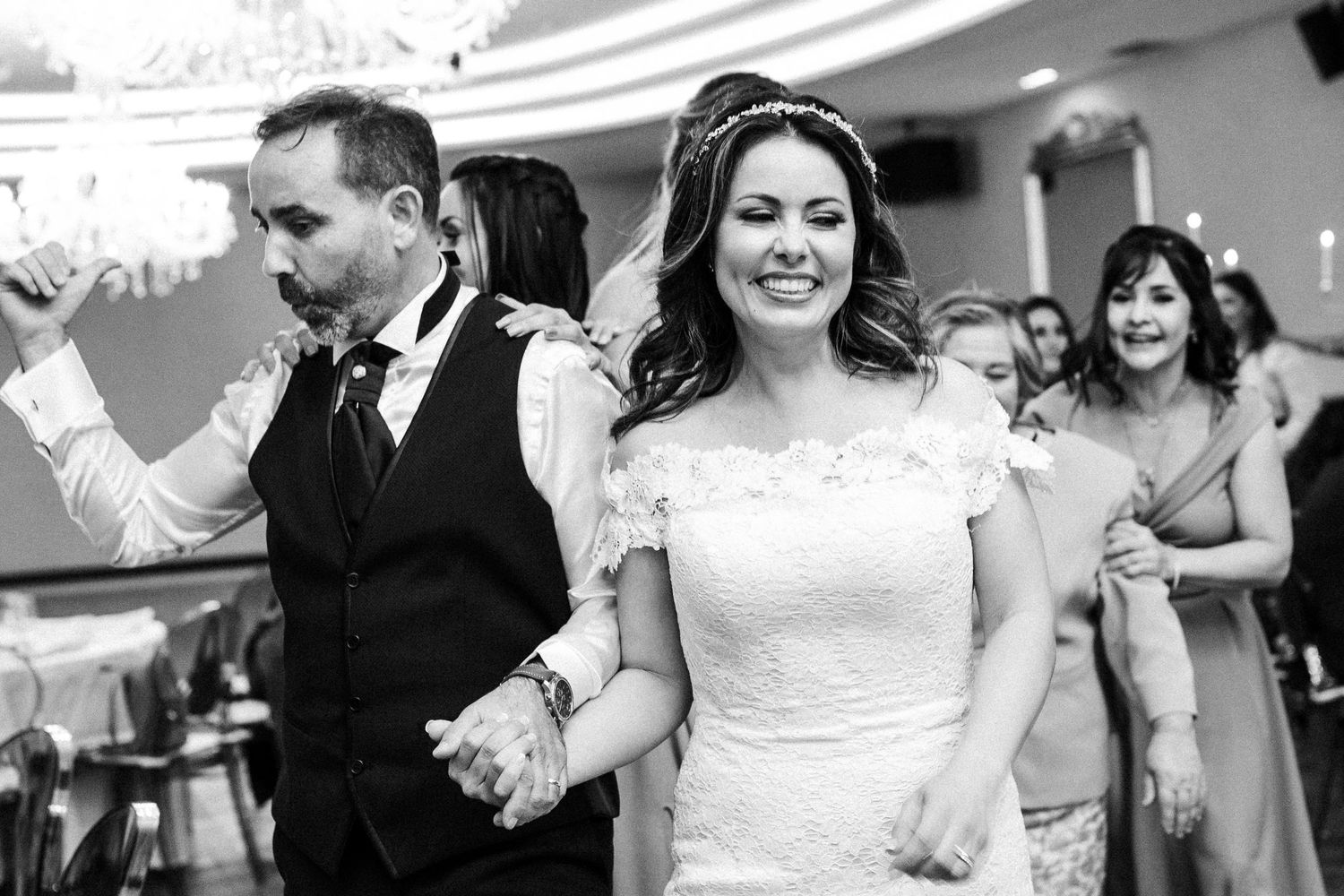 Wedding couple celebrates while dancing through venue with guests cheering.