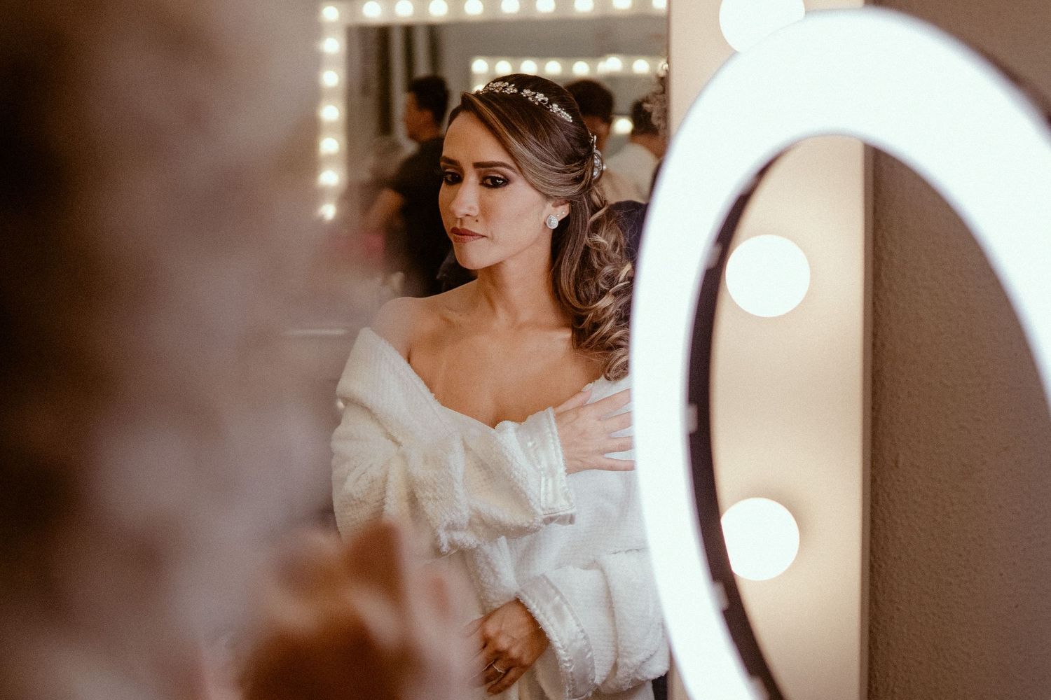 A vintage-inspired bride in a delicate white wedding dress poses in soft backlit studio lighting.