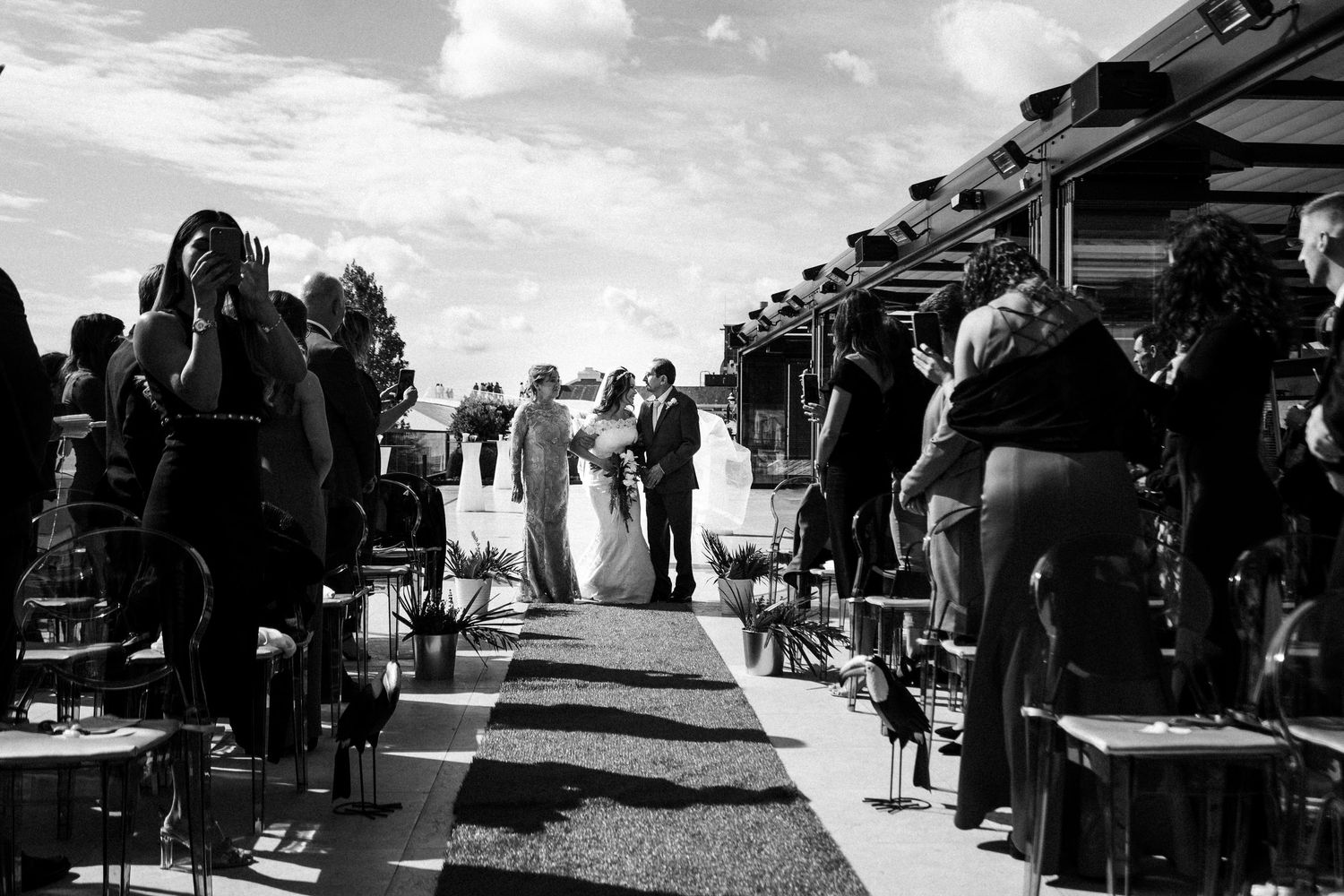 Group of people walking and browsing an outdoor market with tents and stalls on a sunny day.