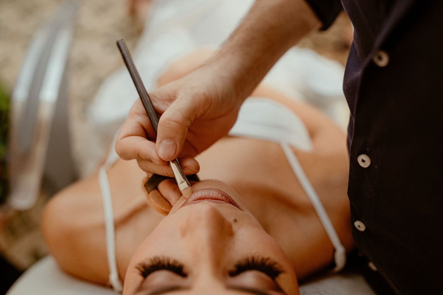 Professional nail technician applies polish during a manicure treatment at a salon.