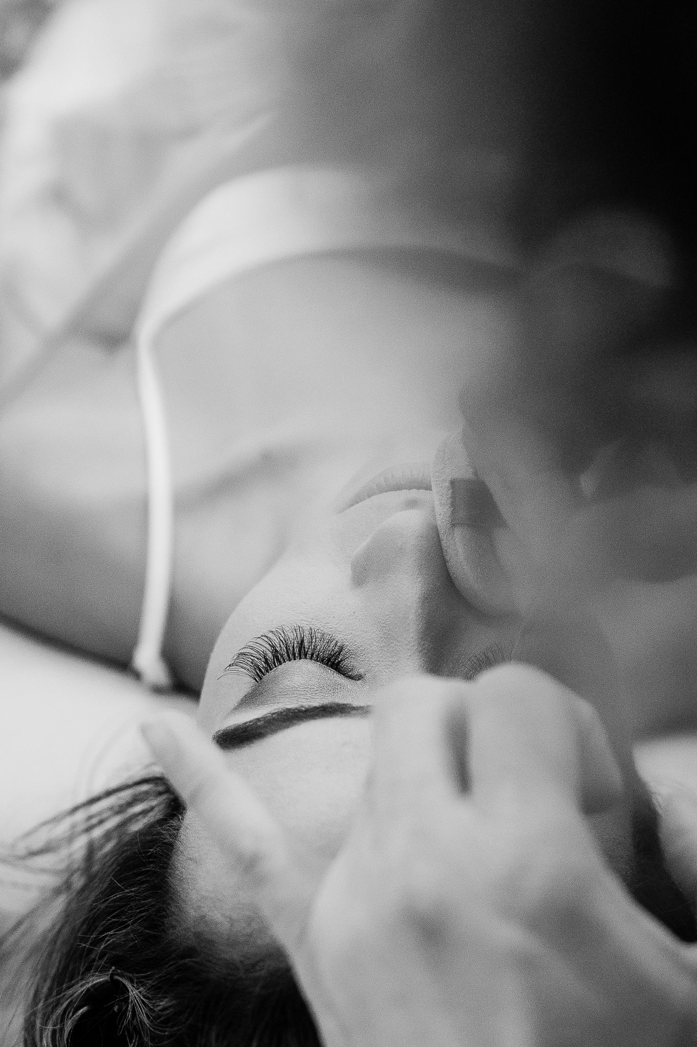 A close-up black and white photograph shows long eyelashes and closed eyes in a dreamy, peaceful pose.